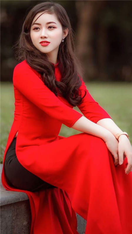 Xem ảnh cô gái xinh đẹp với tà áo dài đỏ rực rỡ ngồi tạo dáng với vòng eo thon